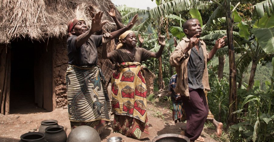 Joyful dance outside a rural hut with lush greenery in the background Joyful dance outside a rural hut with lush greenery in the background