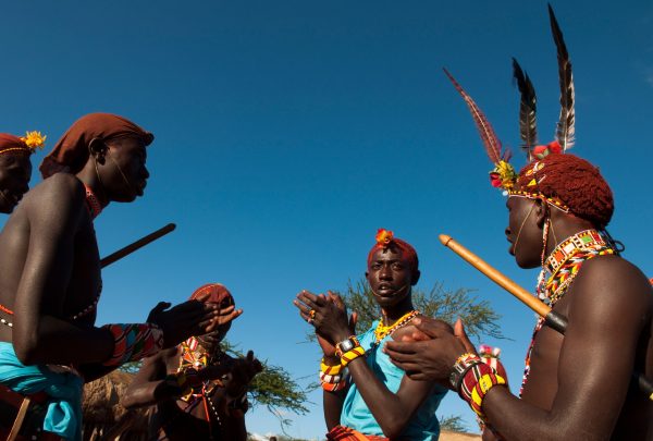 Tribal community members engaged in a vibrant cultural exchange under the open sky. Tribal community members engaged in a vibrant cultural exchange under the open sky.