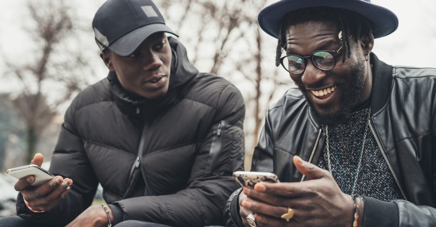 two african friends sitting outdoor and looking the smartphone two african friends sitting outdoor and looking the smartphone