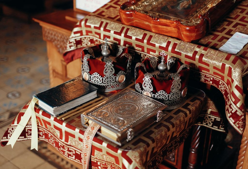 Golden bible, gospel, crowns and cross and icon on red and gold altar in church