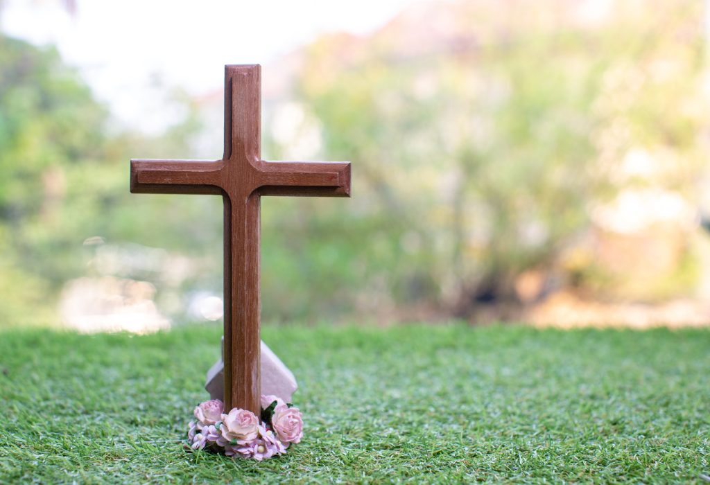 The cross standing on meadow sunset and bokeh background.